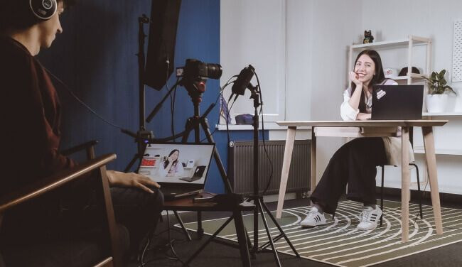 a person sitting at a table with a camera and a person sitting in front of him